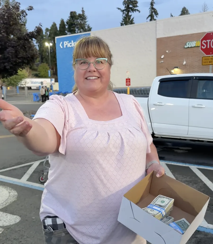 Smiling woman in a store parking lot holding a box of cash from one of our giveaway videos